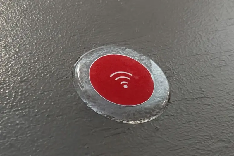 A red Wi-Fi Toque sticker stuck to a dark table top, photographed close up.